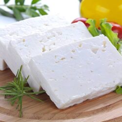 "feta cheese cut in slices, vegetables, herbs and olive oil-the ingredients for a greek salad"